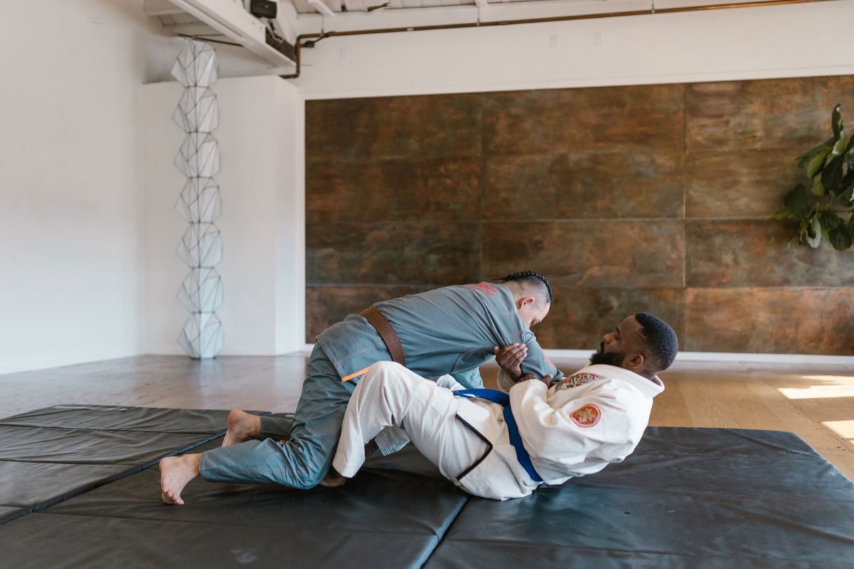 Two adult students practicing jiu-jitsu on the mats