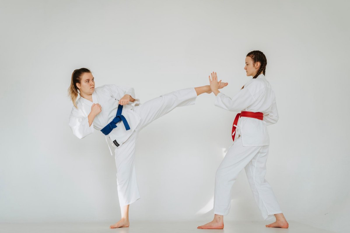 Two karate students practicing a kick and block