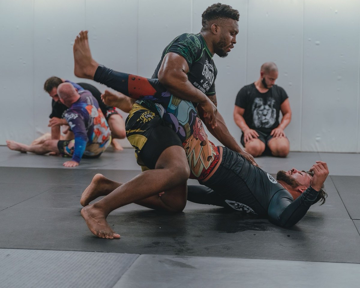 No-gi grappling training in rash guards on black mats