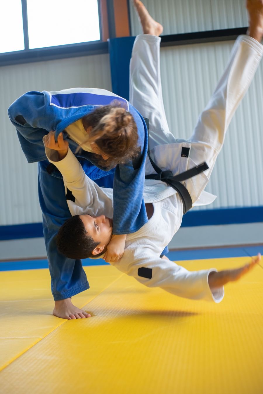 A judoka lifting a partner high into the air for a throw during training