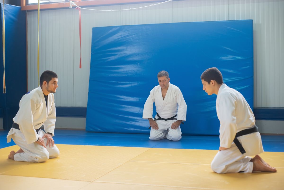 Judo students kneeling and bowing to their sensei at the start of class