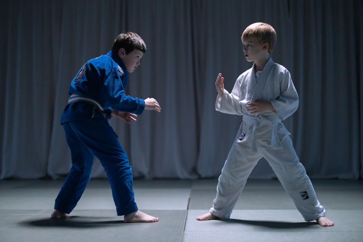 Two young judoka in blue and white judogi facing each other on the mat