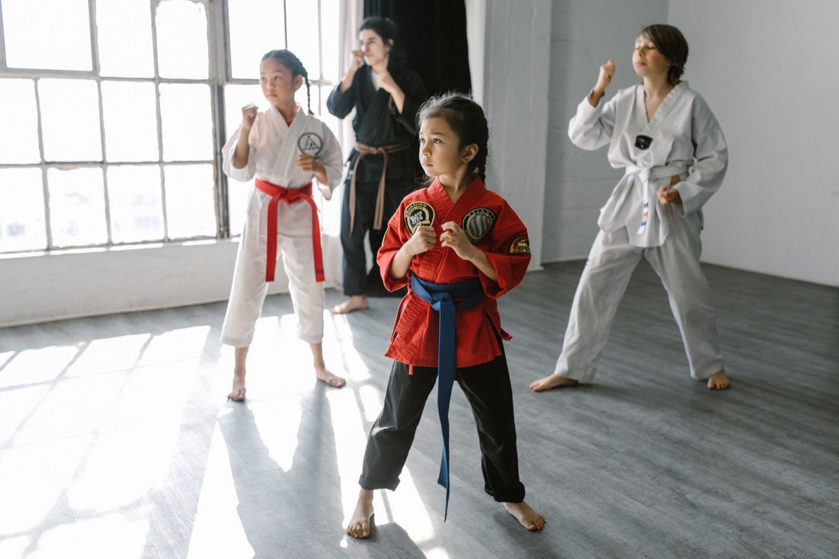 Children in martial arts uniforms practicing their stance in class