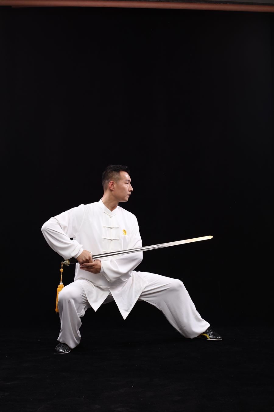 A Kung Fu practitioner in a white uniform performing a straight sword form