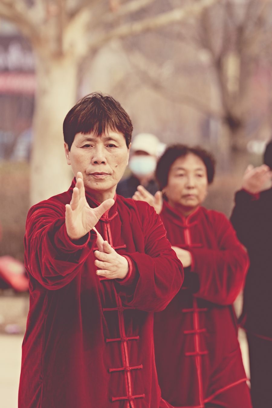 Tai Chi practitioners in red traditional uniforms practicing a form together