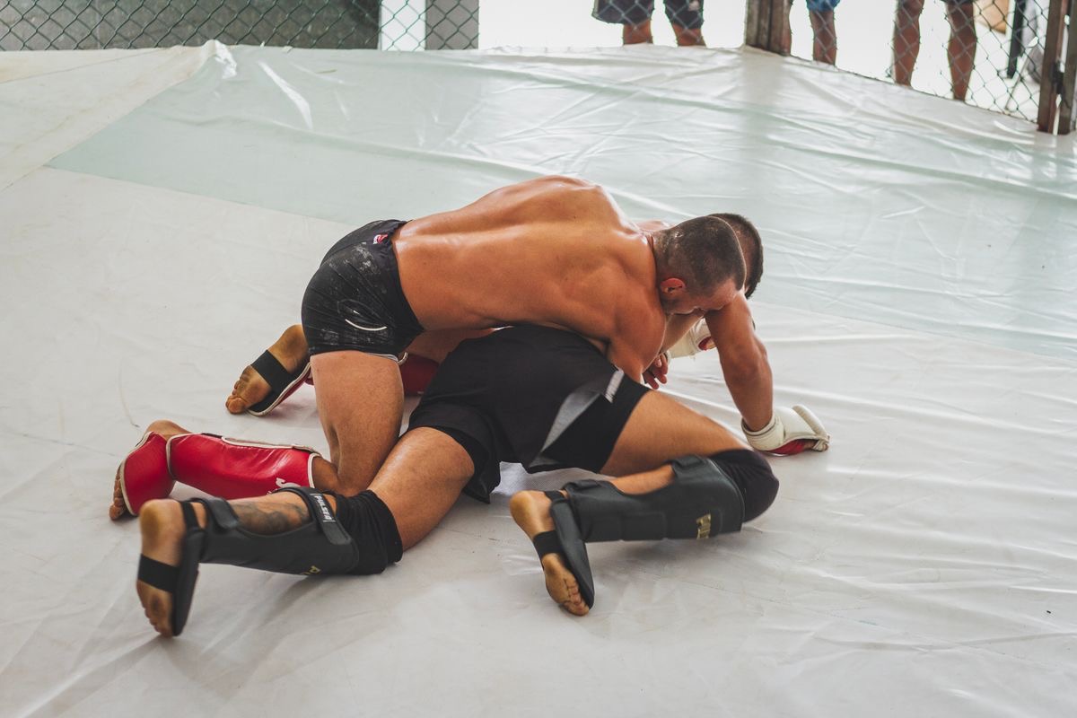 Two MMA fighters grappling on the mat