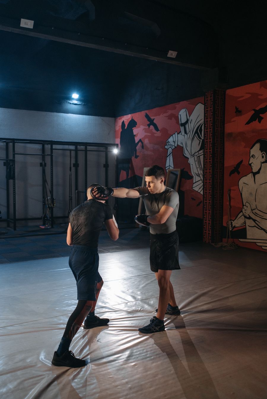 An MMA coach holding a pad while a student throws a punch