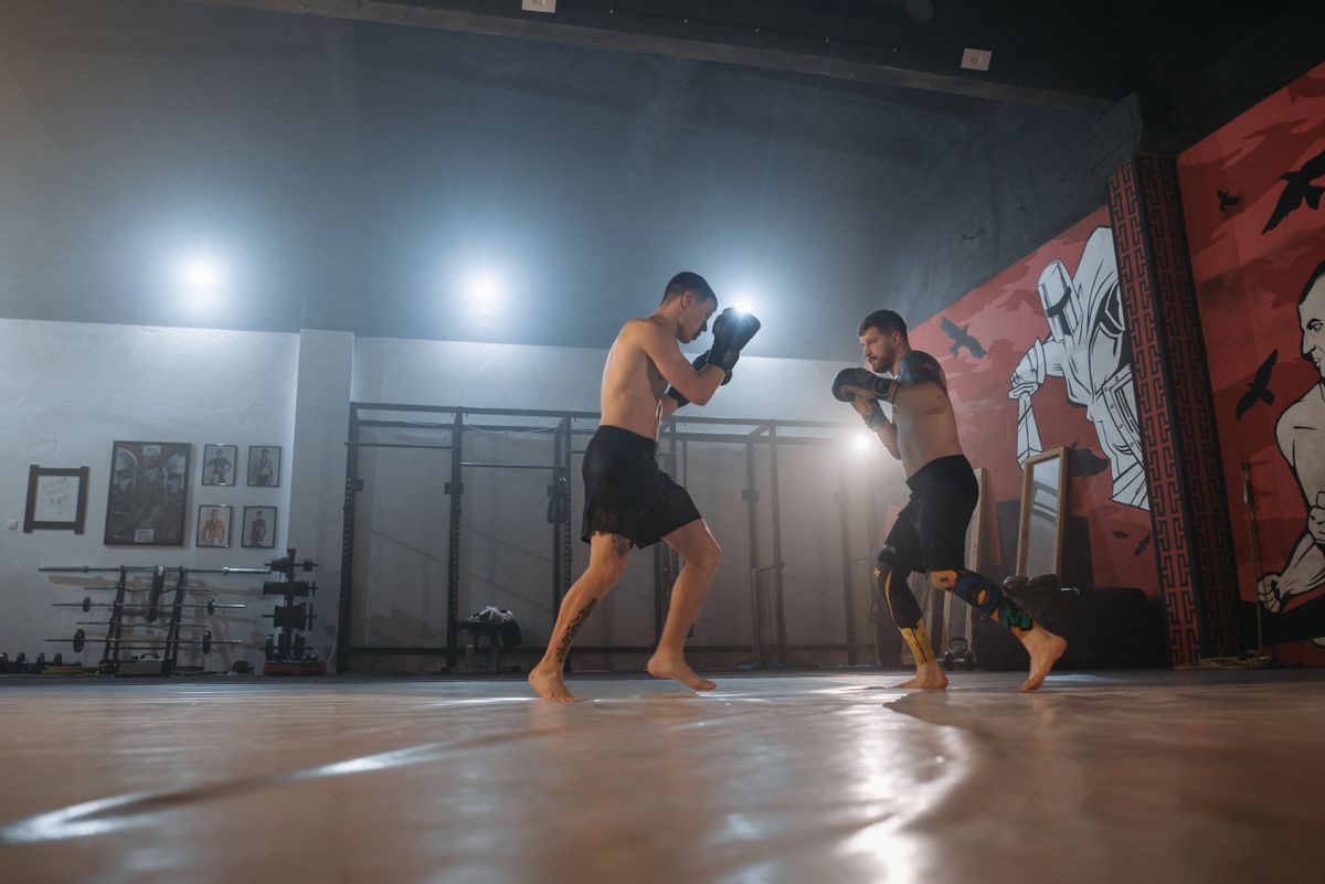 Two MMA students in gloves sparring on the mats
